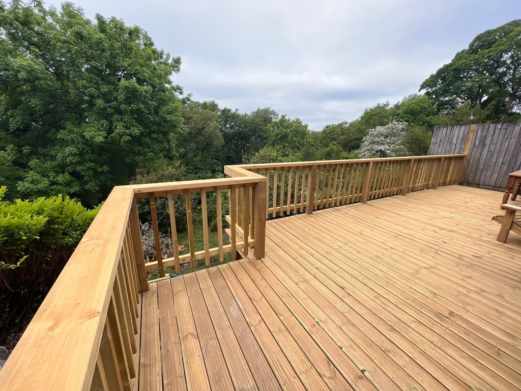 Raised timber deck with matching balustrade overlooking trees, built by PC Landscaping in South Devon