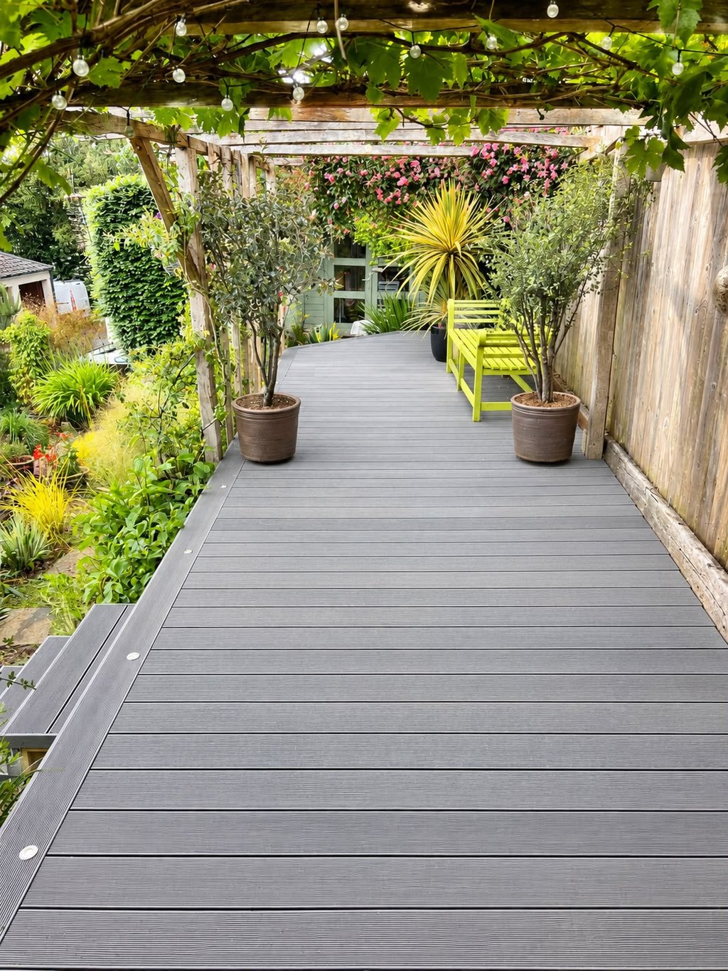 Grey composite decking beneath a timber pergola with potted trees, built by PC Landscaping in South Devon